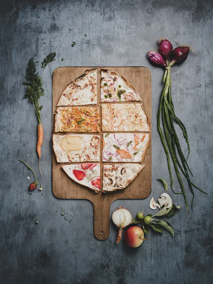 Tarte flambée découpée, entourée de légumes frais
